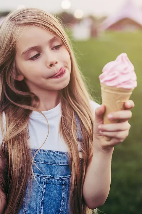 Mädchen genießt Eis auf Wiese
